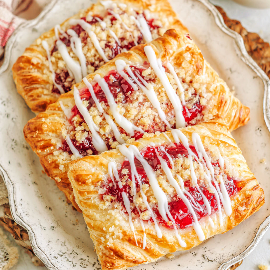 Two Danishes with white icing and cherries on top.