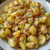 Ein weißer Teller mit Kartoffeln und Bacon.