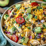 Ein großes, leckeres Hühnersalat mit vielen Zutaten wie Tomaten, Avocado, Koriander, Hühnchen, Kartoffeln und Käse.