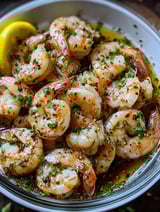 A bowl of shrimp with a lemon wedge on top.