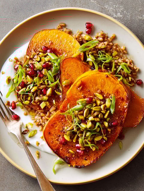A plate of butternut squash steaks with rice and pumpkin seeds.