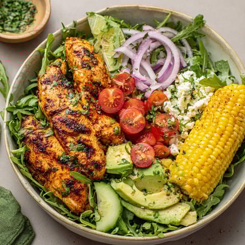 A bowl of grilled chicken with tomatoes and onions.