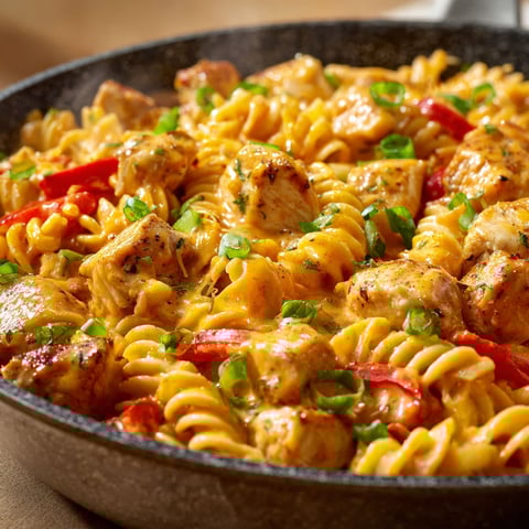 A skillet full of chicken and pasta.